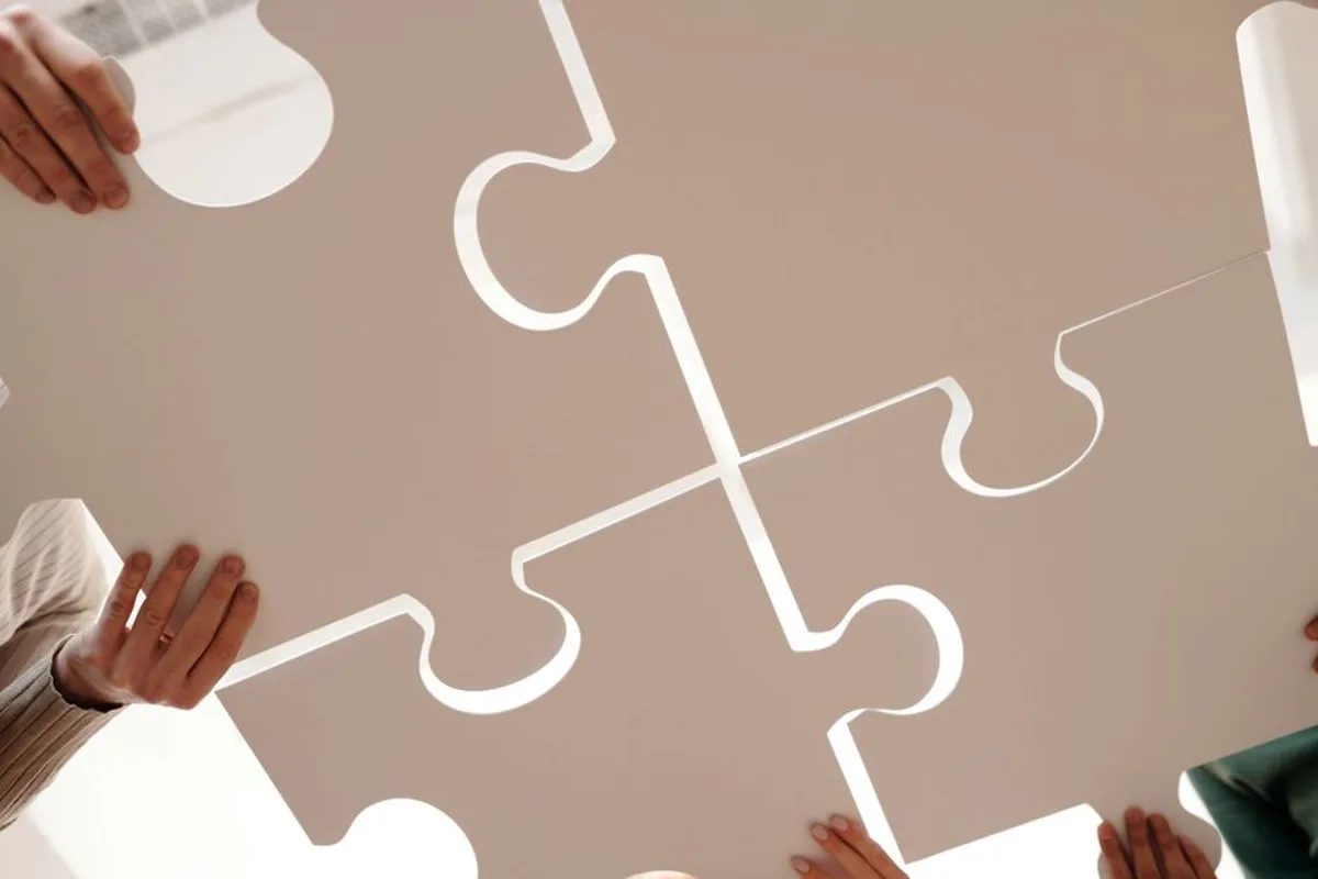Mains assemblant des pièces de puzzle, image des services marketing formant un système cohérent