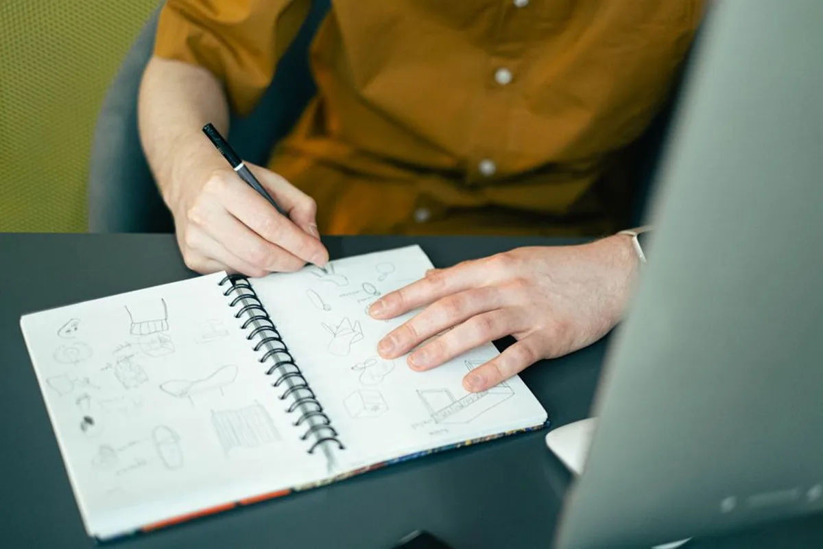 Designer esquissant des propositions de logo au crayon dans un carnet