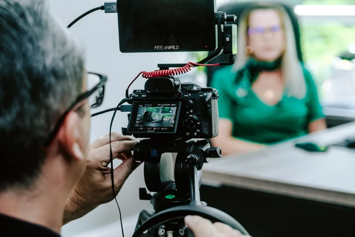 Videographer filming a corporate interview with a professional camera and monitor in an office