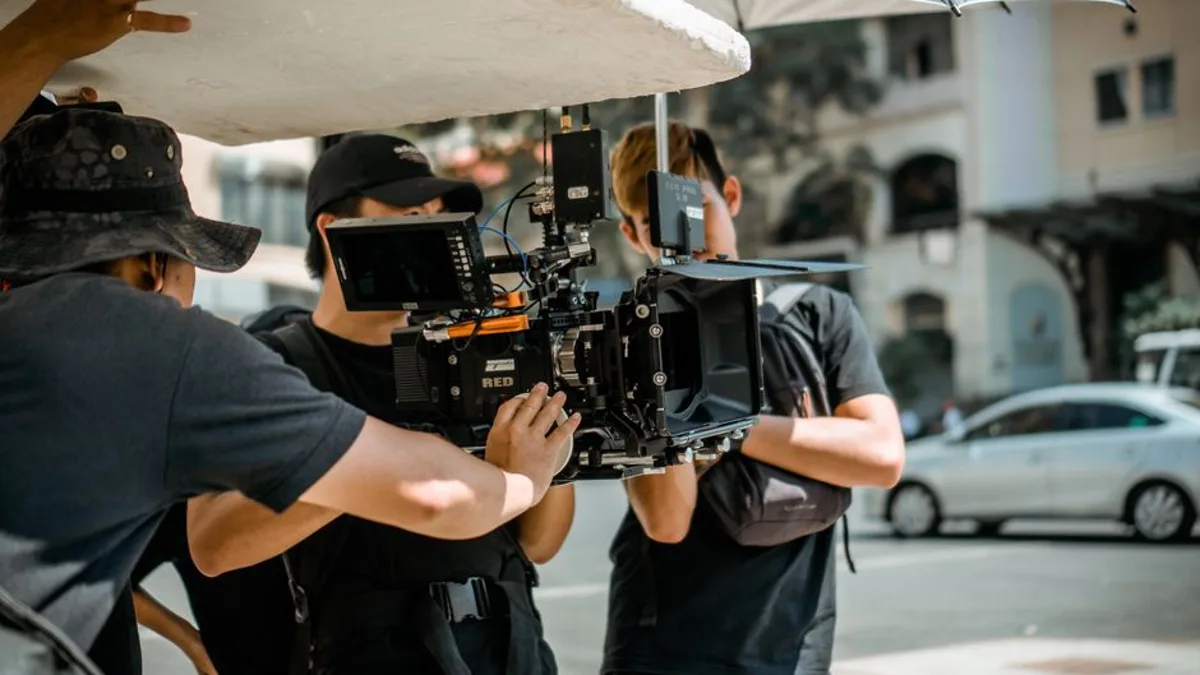 Équipe de tournage avec caméra cinéma RED sur un plateau extérieur, production audiovisuelle professionnelle